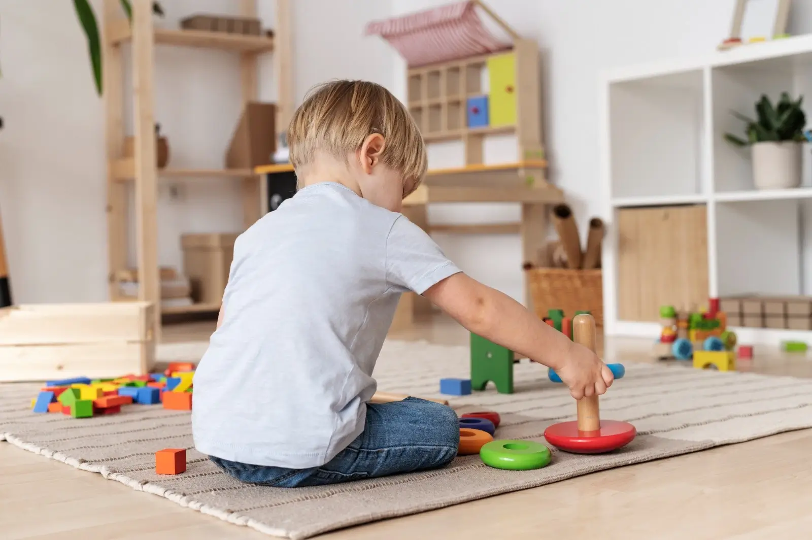 Bir çocuk, renkli ahşap oyuncaklarla oyun oynarken görülüyor. Oyun terapisi sırasında çocukların duygusal gelişimine destek sağlanır ve terapi süreci keyifli bir öğrenme ortamında gerçekleşir.